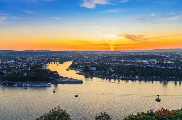 Aerial panoramic view of Koblenz historical city centre and joining Rhine and Moselle rivers, evening twilight view of amazing colorful orange sunset on horizon, Rhineland-Palatinate state