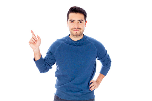 Young man pointing at something imaginary while facing camera cheerfully