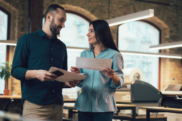 istock Cheerful man and woman in the office with documents in hands 1253536096