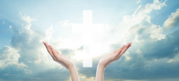 istock Human hands and cross against sky clouds background 1253536164
