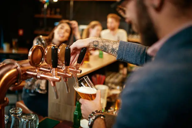 Barman filling pint of beer in glass.