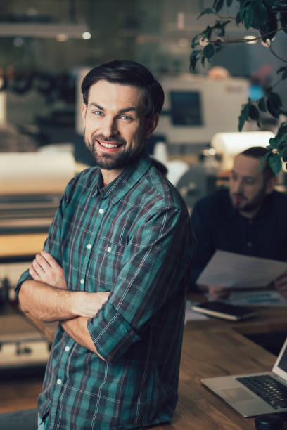 istock Handsome young man posing at his workplace and looking glad 1253538045