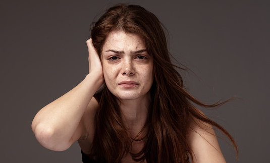 Freckled beautiful young woman crying.