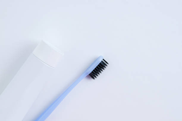 istock Blue toothbrush with black bristles and a tube with toothpaste on a white background. 1253538302