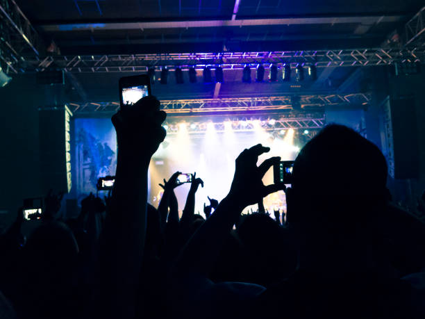 Filming concert on smart phone Close up on a handheld smart phone, recording a live gig. Background is a defocused stage. italian music stock pictures, royalty-free photos & images