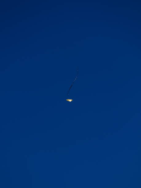 istock yellow paper kite, lit by sunlight, floating under a cloudless blue sky. 1253543573