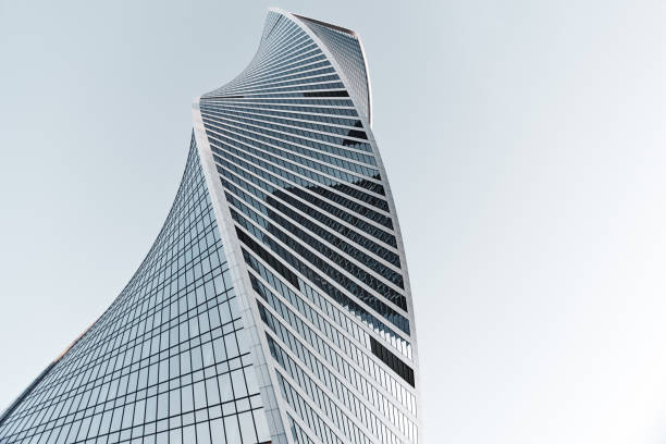 low angle view to modern glass skyscrapers in business district with light blue sky - multi story building imagens e fotografias de stock