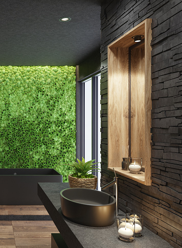 Trendy and modern home spa bathroom with matte black tiles, black stacked stone wall and lots of natural light. Green moss plant wall for cozy interior. Modern black bath tub. Wooden tiles on some walls. Candles light. Big panoramic windows. Nature wood texture stone floor. 3d rendering.