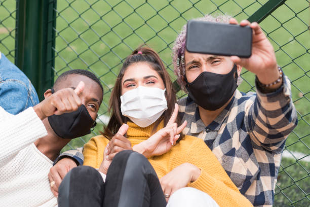 istock friends having fun in the park wearing their masks while taking a selfie 1253546646