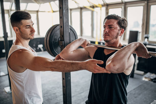 istock Personal trainer assisting a man in weightlifting training 1253546841