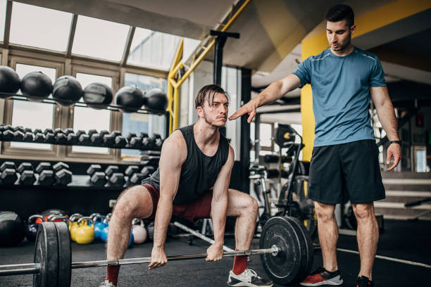 istock Personal coach helping a man in weightlifting training 1253547501