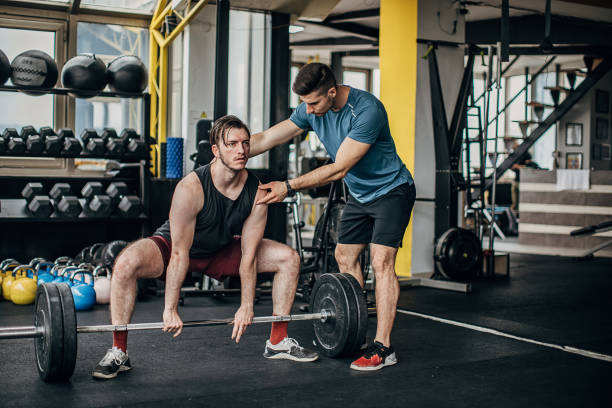 istock Fitness trainer helping a man in weightlifting training 1253547530
