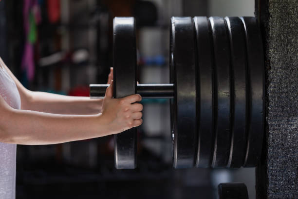 istock Strength Workouts: an  plus size Woman Taking a Disk Weight from the Rack 1253547637