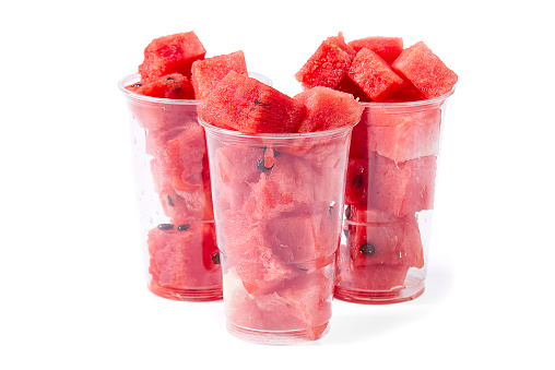 Close up sliced red watermelon cubes in plastic cup isolated on white