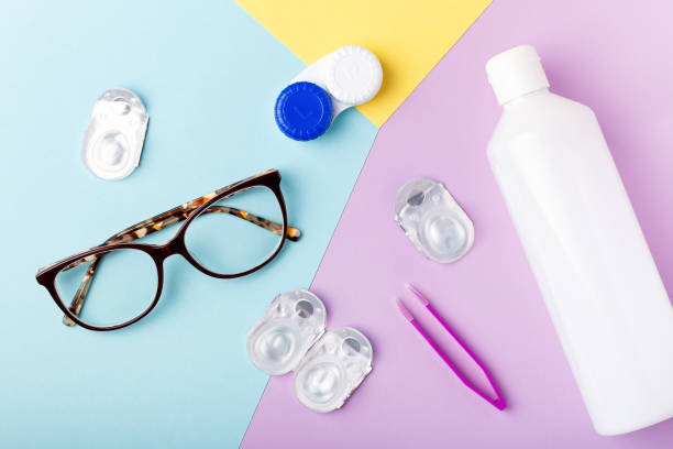 Contact lens kit with bottle of lens solution, case, tweezer on multicolor background, copy space, top view