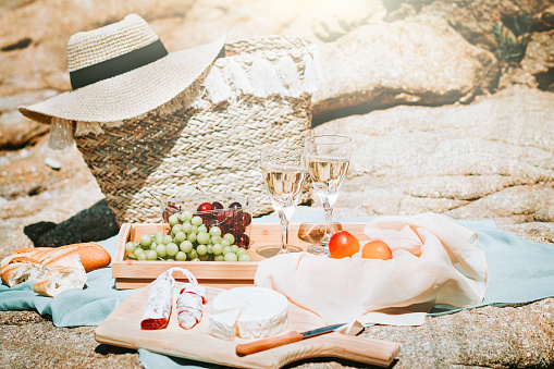 Romantic picnic for two on sea beach with white wine, fruits, bread and cheese. Mediterranean picnic with two glasses of wine, grapes, cherry
