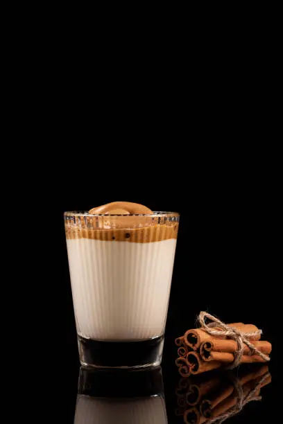 Photo of Dalgona coffee - the Korean coffee drink on black background. Instant coffee or espresso powder whipped with sugar and hot water. Iced whipped dalgona coffee concept