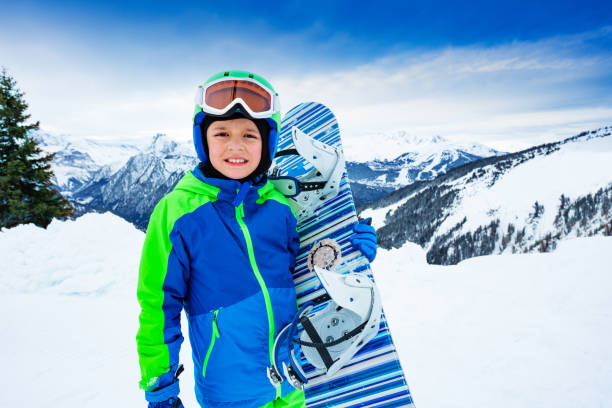 istock Boy hold snowboard in hands over mountains view 1253559356