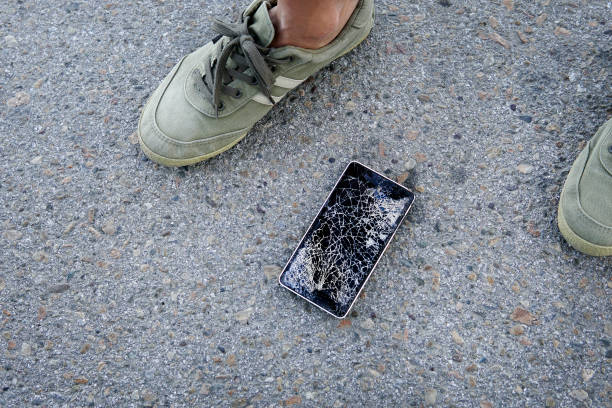 istock Broken, destroyed, ruined modern mobile smartphone, cell phone, mobile phone, phone. Broken, cracked screen and damages. Phone with broken screen on asphalt. Someone dropped device. 1253559777