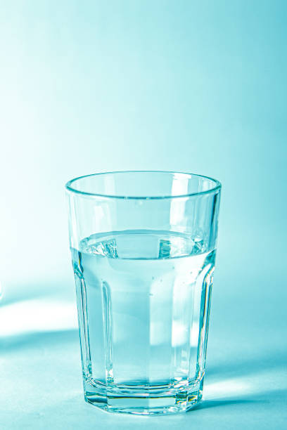 istock Glass with pure clear melt water on a blue background 1253562593