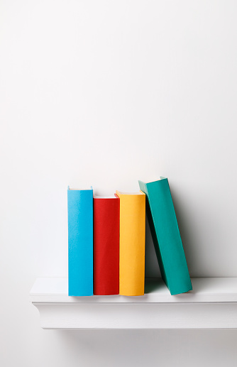 Colored books on a shelf on white background with copy space.