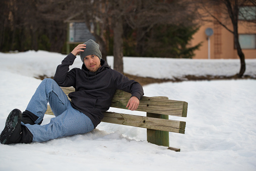 Snowboarder sitting on a bench buried in snow looking at camera