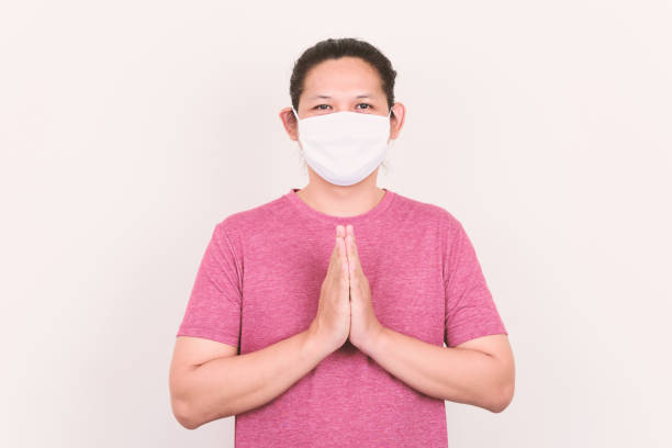 istock Asian man wearing white fabric mask and showing Thai greeting 1253574497