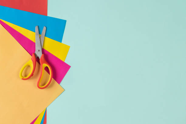 istock Colored sheets of paper and scissors on a light blue background. 1253574659