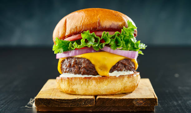 cheeseburger denso con formaggio americano, pomodoro lattuga e cipolla - pan brioche foto e immagini stock
