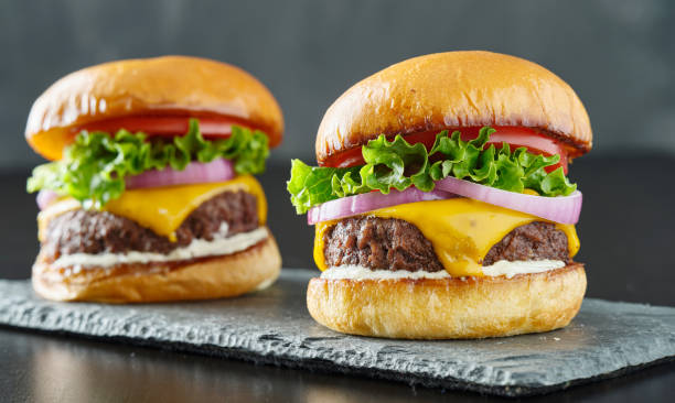 istock two beefy cheeseburgers with american cheese, lettuce tomato and onion 1253576713