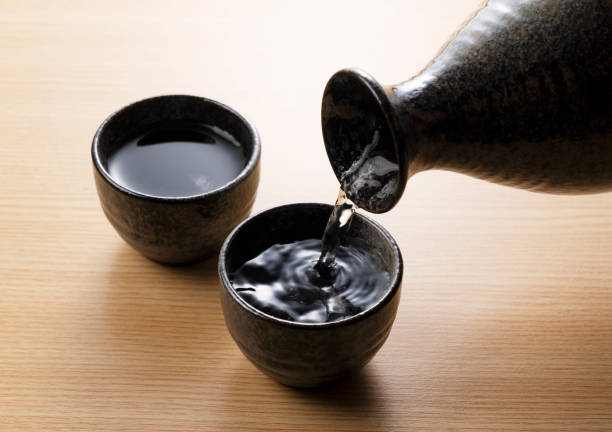 istock Pouring sake into a sake cup set against a wooden backdrop 1253580489