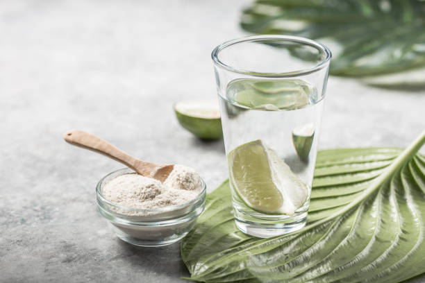 Collagen Powder and glass of water with  slice of Lime; Vitamin C . Collagen supplements may improve skin health by reducing wrinkles and dryness. stock photo