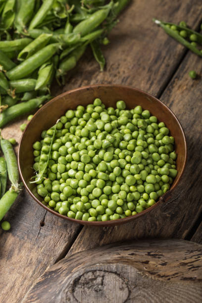 istock Young fresh green peas on wooden  table viewed from above 1253593169