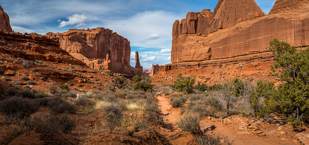 Scenic view looking down into a canyon surrounded by monolithic sandstone rock structures seen along the Park Avenue Trail, Arches National Park, Moab, Utah