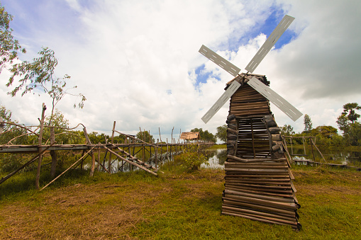 Wind turbine built from wood In a meadow near the lake On a day with beautiful clouds