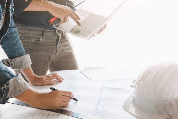 istock Engineer are discuss planning to drawing house structure on Blueprint and design graphic model house on laptop computer for his customers.Engineering and construction concept. 1253599969