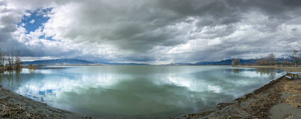 Dramatic Sky over Utah Lake Panorama Dramatic cloudscape over calm and reflective Utah Lake with snowcapped mountains in the distance, Utah Lake State Park, Provo, Utah lake utah stock pictures, royalty-free photos & images