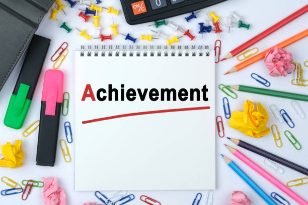 istock On the table is a calculator, diary, markers, pencils and a notebook with the inscription - Achievement 1253600418