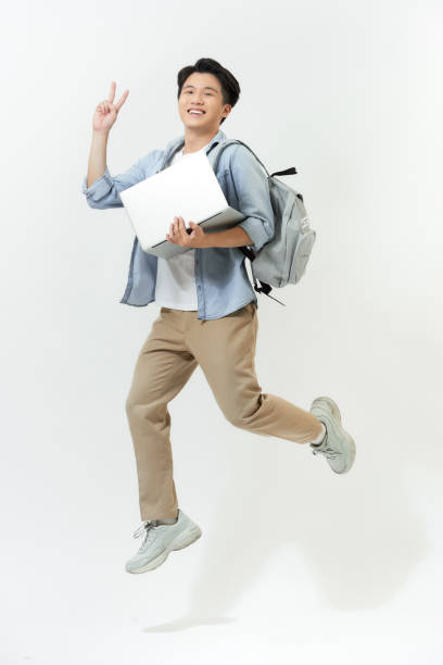 istock Happy jumping Asian programmer with laptop on color background 1253601346