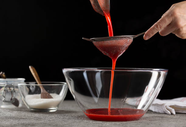 istock Strainer Syrup Making Strawberry Jam Pouring Strawberry Syrup, close up 1253602233