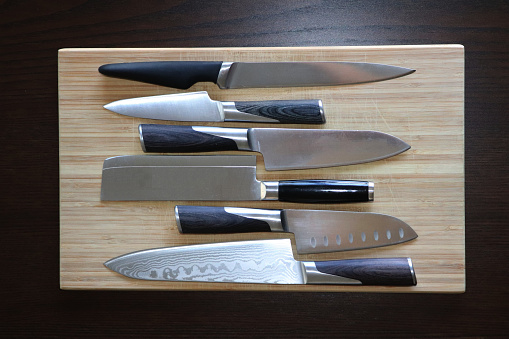 Top-down view of a wooden cutting board with knives lying on it