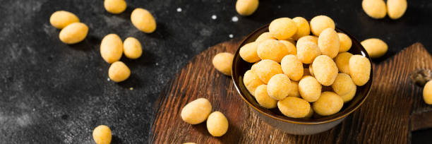 istock Fried peanuts in cheese sauce in a bowl on the black kitchen table. Banner with space for text 1253605267