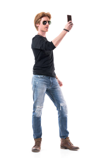 istock Young handsome stylish red haired man displeased while looking at photos on cell phone 1253608025