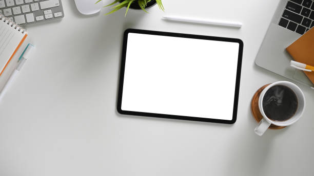 a imagem de vista superior do espaço de trabalho branco é cercada por um tablet de tela em branco em branco e vários equipamentos. - messy adhesive note office computer - fotografias e filmes do acervo