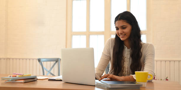 istock A university student is learning lessons online while sitting at the wooden working desk. 1253608958