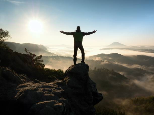 istock Happy Man With Raised Arms Gesture Triumph On Exposed Cliff. 1253609351