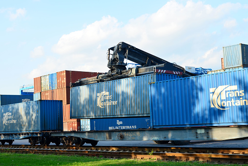 Russia, Moskow region - May 13, 2019: Loading shipping containers by richtracker on the freight rail car at  Transport-Logistics Centre BELINTERTRANS. TransContainer is a Russian transport company