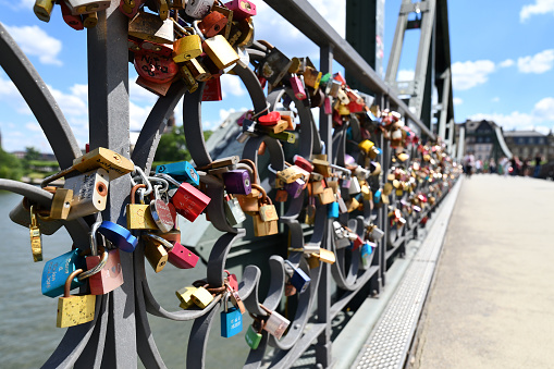 Frankfurt am Main, Germany - June 2020: Many love padlocks attached to bridge called 'Eiserner Steg' on sunny day.