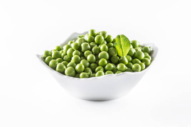 istock Green raw peas in pocelain bow isolated on white background 1253617934