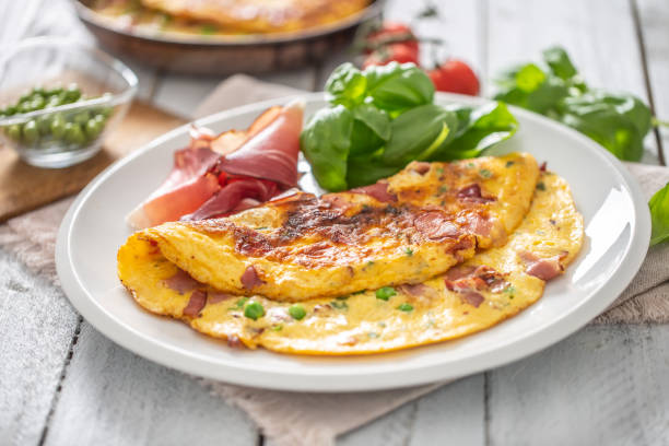 istock Omelette with prosciutto peas basil tomatoes and herbs on white plate 1253617937